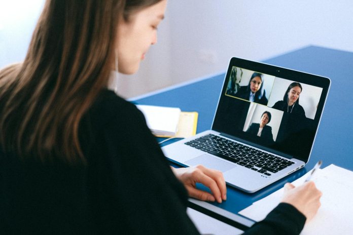Photo by Anna Shvets A woman engaging in a video conference using a laptop at home, taking notes.